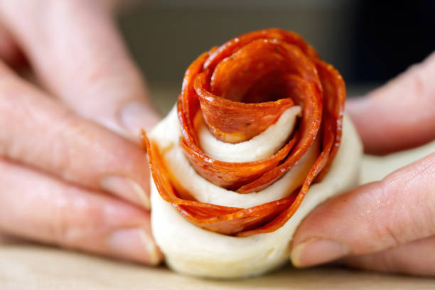 la mujer está haciendo un bocadillo de pepperoni en forma de rosa. pastelería con salami. hojaldre casero listo para hornear - appetizer people marinara cheese fotografías e imágenes de stock