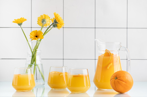 Fresh squeezed orange juice and spring yellow flowers in a vase. Stock photo