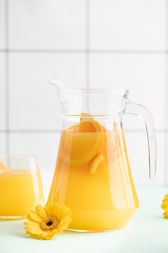 A pitcher of fruit juice. Orange  juice on the white table.