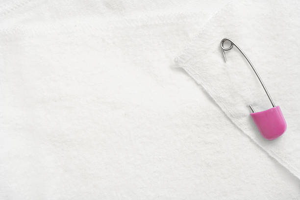 Isolated silver metal safety pin used by tailors for sewing and clipping pieces of textile together on the white background