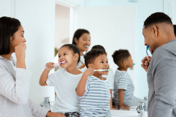 aufnahme einer schönen familie, die sich zu hause gemeinsam die zähne putzt - mirror mother bathroom daughter stock-fotos und bilder