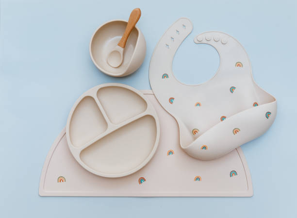 istock Flat lay composition with silicone baby bib and beige dishware on blue background. Flat lay, top view 1373843332