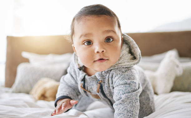 Shot of an adorable baby boy playing on the bed at home Watch me do my thing baby boy stock pictures, royalty-free photos & images