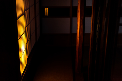 Traditional Japanese machiya house or ryokan restaurant at dark evening night with illuminated yellow light lamp shoji sliding paper door nobody in hall