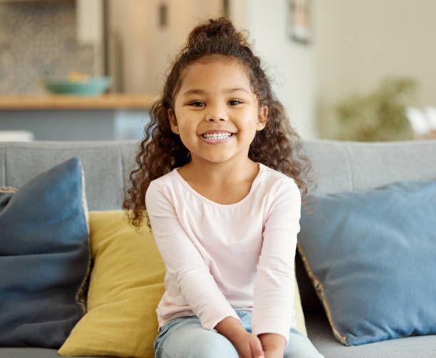 retrato de una niña sentada en el sofá de casa - 4 5 años fotografías e imágenes de stock