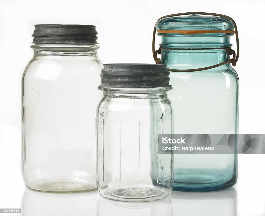 Three Antique Canning Jars Three very old canning jars with two types of lids photographed on a white reflective background. Airtight Stock Photo