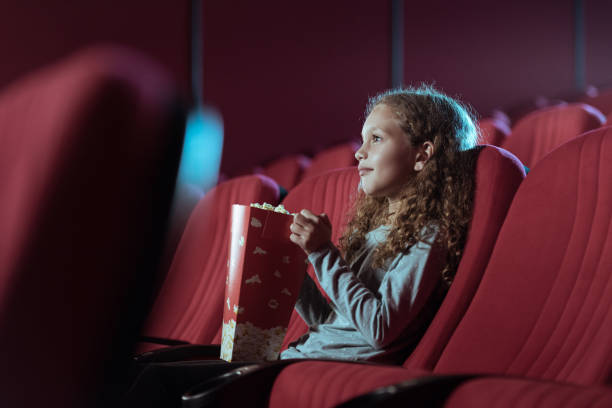Little girl in cinema watching movie stock photo