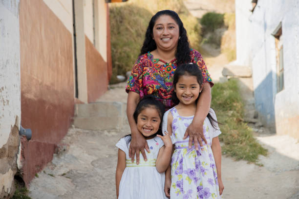 Latin mother with her two happy daughters outside her house in rural area-Hispanic mother hugging her daughters Latin mother with her two happy daughters outside her house in rural area-Hispanic mother hugging her daughters latin stock pictures, royalty-free photos & images