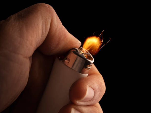 Hand Lighter Hand lightning a lighter with a flame freezed in motion on a black background. cigarette lighter stock pictures, royalty-free photos & images