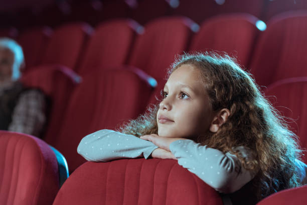 kleines mädchen im kino beim anschauen eines films - cinema theater stock-fotos und bilder