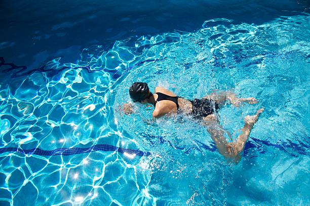 negro traje de baño azul mujer nadando estilo de natación en la piscina de agua - braza fotografías e imágenes de stock