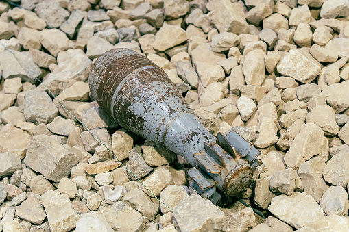 An unexploded mortar mine lying on the rocks. Clearance of unexploded shells after a battle in the war.