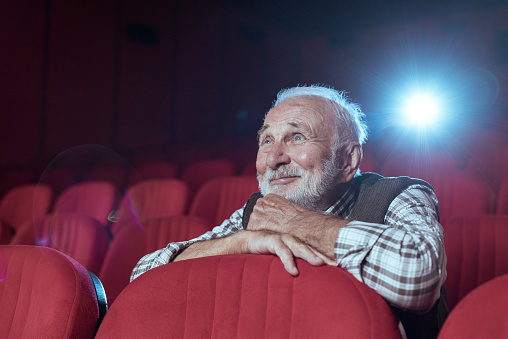 Senior men with beard watching movie in cinema
