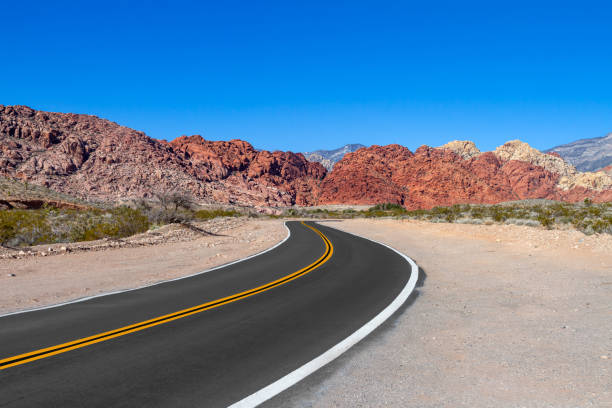 uma estrada curva na área de conservação nacional red rock canyon em nevada - arid climate asphalt barren blue - fotografias e filmes do acervo