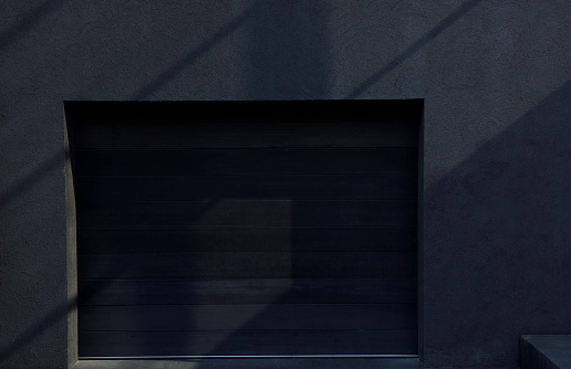 Close-up of black garage door with sunlight.