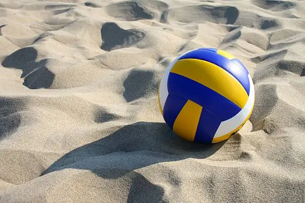 Beach volleyball lying in sand.