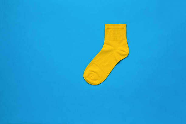 istock Bright yellow sports sock on a blue background. Flat lay. 1374115975