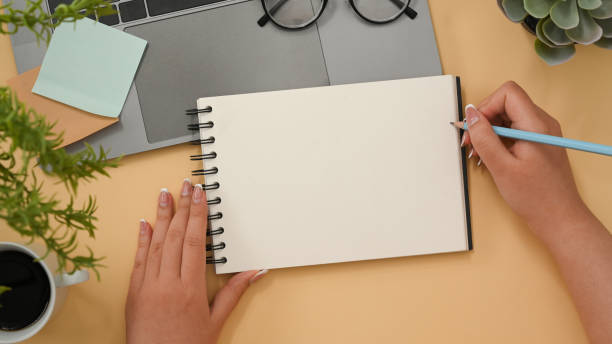 istock Female officer wiring her ideas on spiral notepad. top view 1374117577