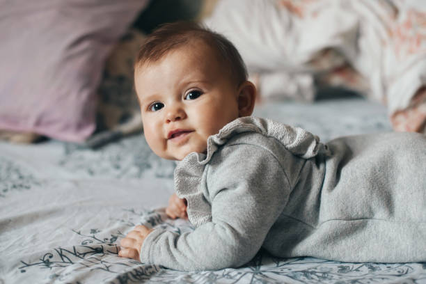 istock Caucasian baby girl wearing bodysuit crawling on bed while looking at camera. Beautiful closeup portrait. 1374118631