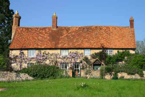 Stone built wisteria clad traditional cottage in rural Oxfordshire England