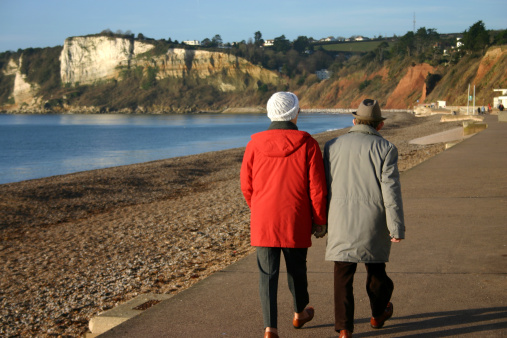 Elderly couple stroll the promenade at Seaton, Devon, England on a Sunday morning