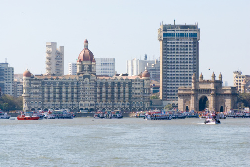 Panorama of Mumbai. Hotel 'Taj' and monument The Gateway of India. Located on the waterfront in Apollo Bunder area in South Mumbai, The Gateway of India was built to commemorate the visit of King George V and Queen Mary to Bombay, prior to the Delhi Durbar, in December 1911. Its design is a combination of both Hindu and Muslim architectural styles, the arch is in Muslim style while the decorations are in Hindu style.