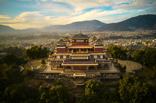 High angle view of Buddhist pilgrimage site situated on northern hill in Kathmandu Valley with city and mountains in background.