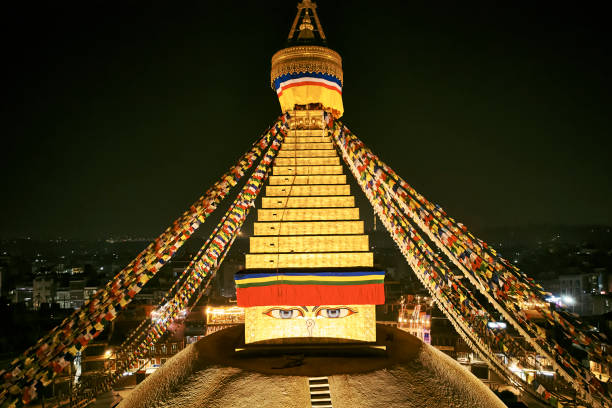 Nighttime partial view of illuminated Buddhist temple surrounded by Kathmandu, Nepal’s capital city.