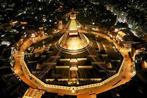 Buddhist temple in Kathmandu at night with decorative wisdom eyes, prayer flags, and massive mandala making it one of the largest spherical stupas in the world.