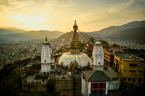 High angle view of tourists visiting Stupa at Swayambhu, a hilltop site in Nepal sacred to Buddhists and Hindus with shrines, temples, and monastery.