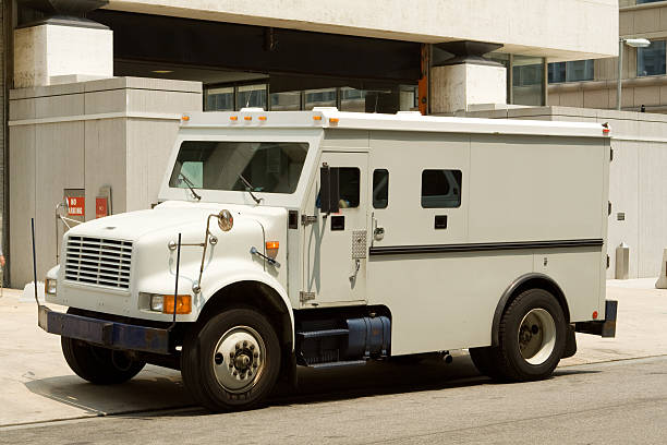 Side View Armoured Armored Car Parked on Street Outside Building Side view of gray armored truck parked on street making a cash pickup. - See lightbox for more armored vehicle photos stock pictures, royalty-free photos & images
