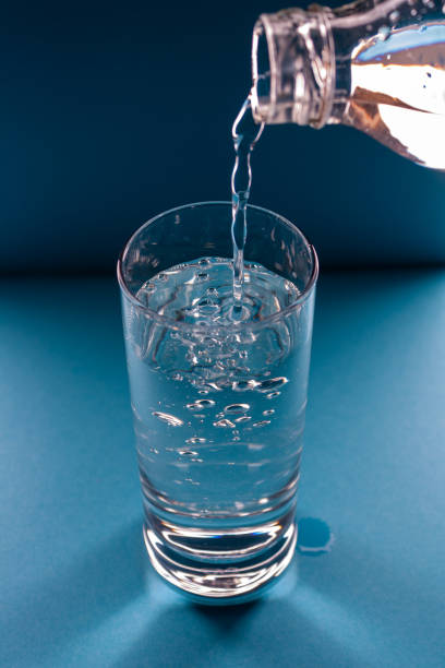 istock water pours from a bottle into a glass on a blue background, top view 1374277589