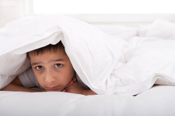 istock Sad little boy laying under blanket 137432892