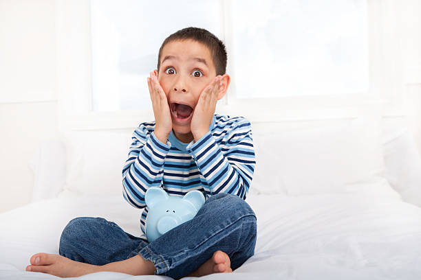 istock Shocked boy holding piggy bank 137432901
