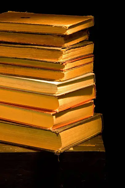 Vintage, antique stack  of books painted with light against black background