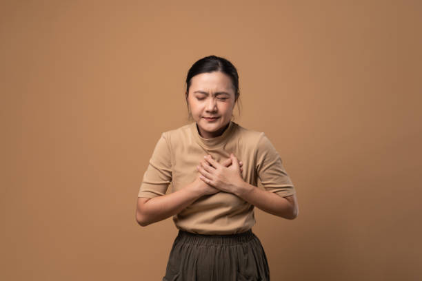Asian woman was sick with chest pain isolated on beige background. Asian woman was sick with chest pain standing isolated on beige background. nausea photos stock pictures, royalty-free photos & images