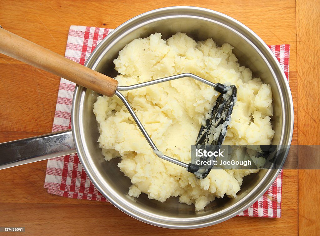 Making Mashed Potato Seasoned potatoes being mashed in stainless steel saucepan. Potato Masher Stock Photo