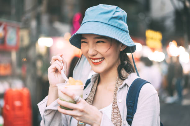 giovane adulto asiatico foodie donna zaino viaggiatore che mangia dessert asiatico a chinatown street food. - bangkok thailand asia thai culture foto e immagini stock