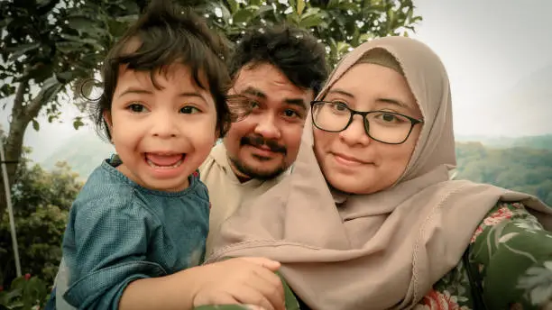 husband taking a selfie with his hijab wife and daughter