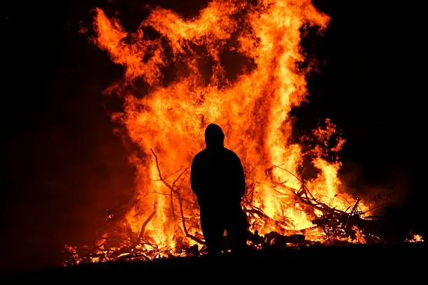 Male silhouette in front of large bonfire