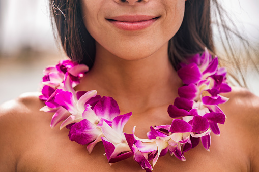 Lei hawaii welcome necklace of fresh orchids flowers garland on woman's neck. Aloha spirit. Hula dancer at luau beach party