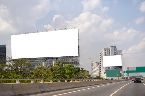 Large horizontal blank sign on a highway in Bangkok, Thailand. Traffic and sky.