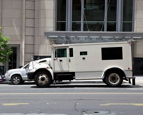 Side view of gray armored double parked on street making a cash pickup.  - See lightbox for more