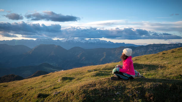 istock Woman sitting on grassy hill 1374414818