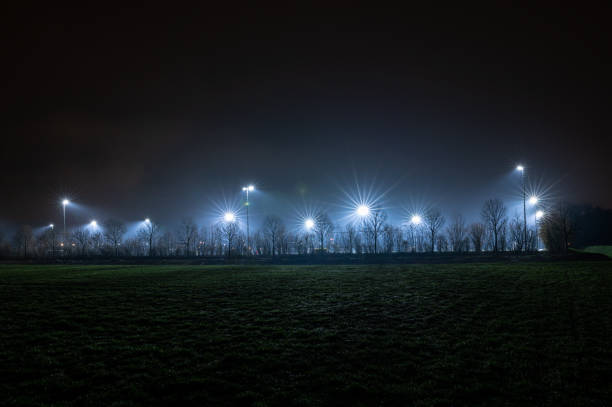 A sports field where training takes place is illuminated by light poles in the evening.