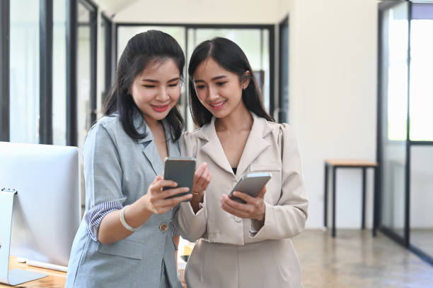 istock Two young businesswoman taking a break in office and using smart phone for checking social media. 1374451703