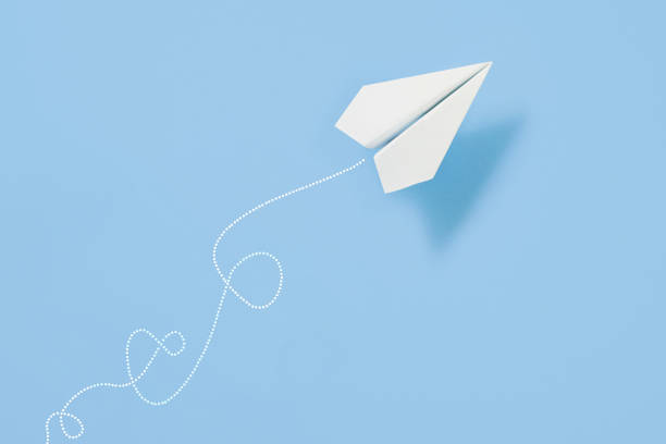 White paper airplane path on blue background with copy space