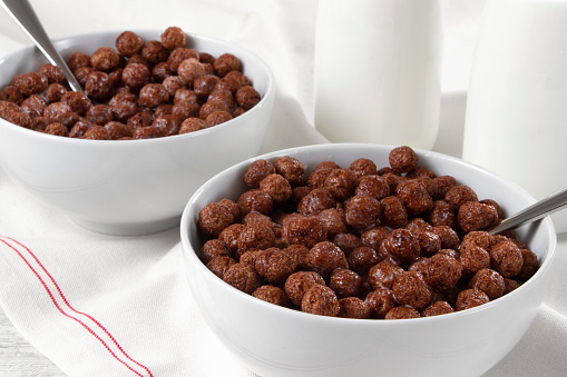 Sweet chocolate cereal bowls with bottle of milk on breakfast table