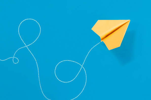 Yellow paper airplane path on blue background with copy space