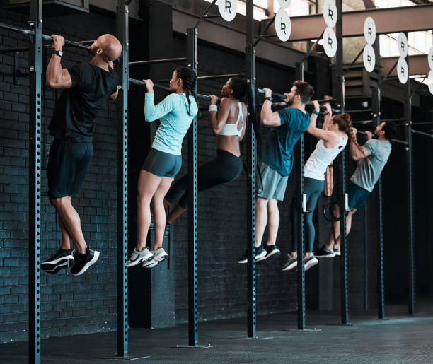 shot of a group of people completing pull ups together - crosstraining imagens e fotografias de stock